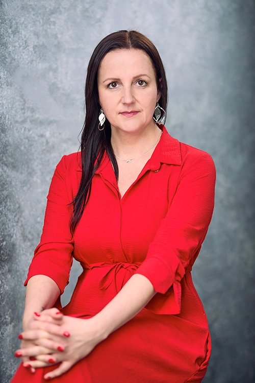 Karolina Maciejczyk is sitting on a chair and is wearing a red dress