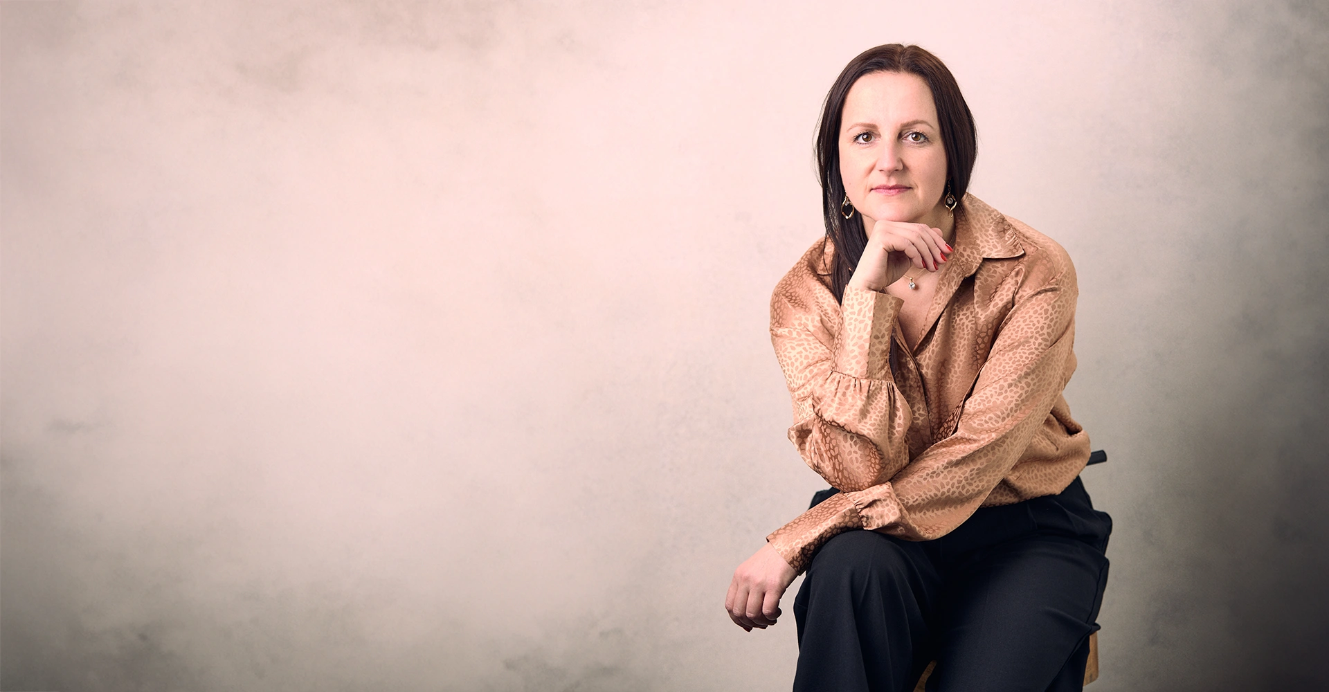 Karolina Maciejczyk in a beige shirt sits and rests her chin on her hand
