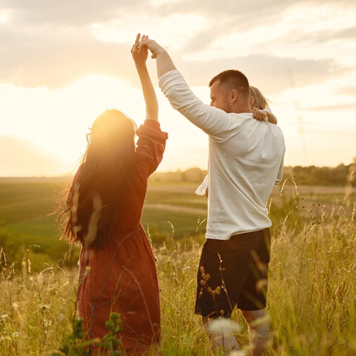 Happy family in a meadow with a child in their arms